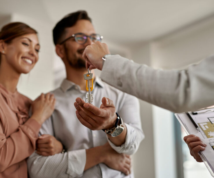 Close-up of real estate agent giving new house keys to a couple.
