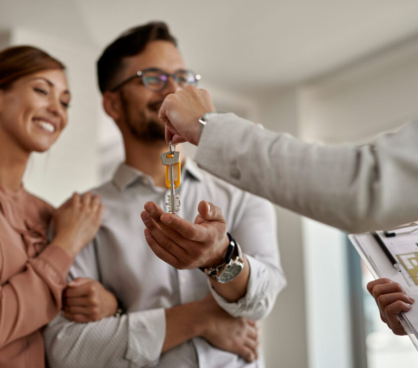 Close-up of real estate agent giving new house keys to a couple.